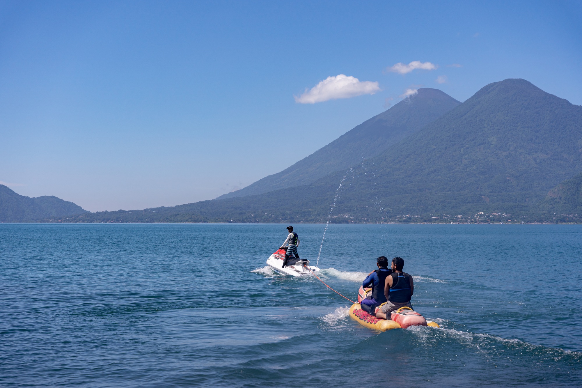 Young Hispanic Men Tubing on Airhead Hot Dog in Atitlan Lake, Guatemala